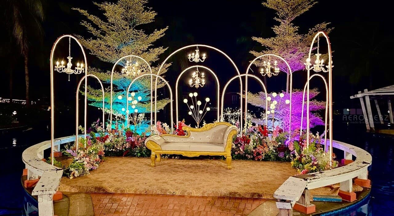 A waterside mandap lit with chandeliers and dressed in seasonal florals